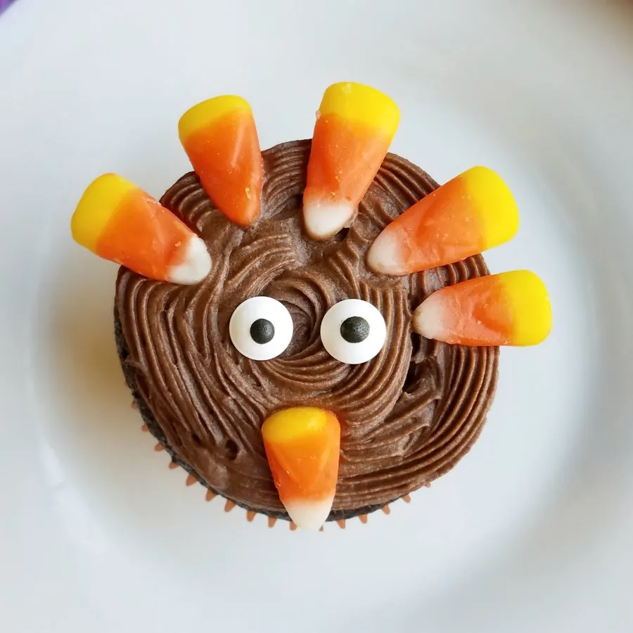 tom the turkey cupcake with eyes and candy corn candies.