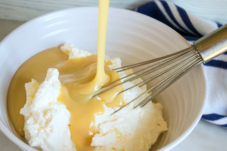 pouring sweetened condensed milk over whipped cream.