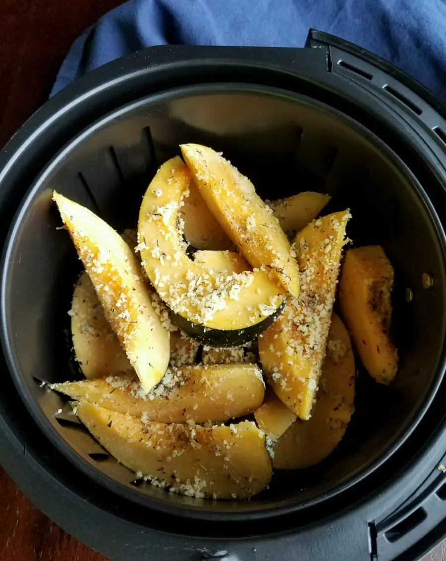 slices of acorn squash in air fryer basket ready to cook.