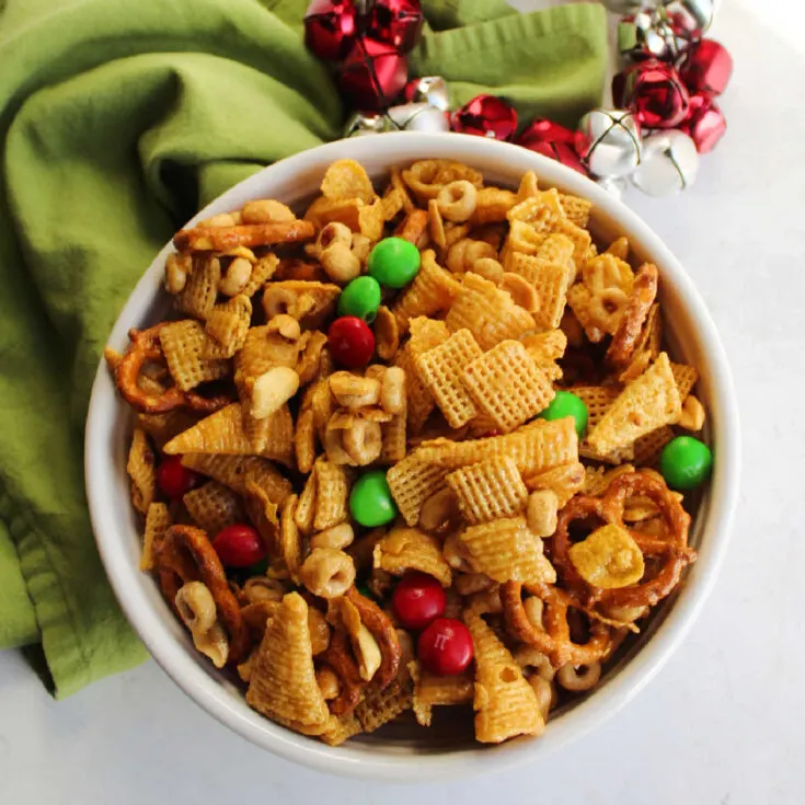 Bowl of caramel snack mix with bugles, pretzels, peanuts, Chex, corn flakes, M&Ms and more, ready to eat.