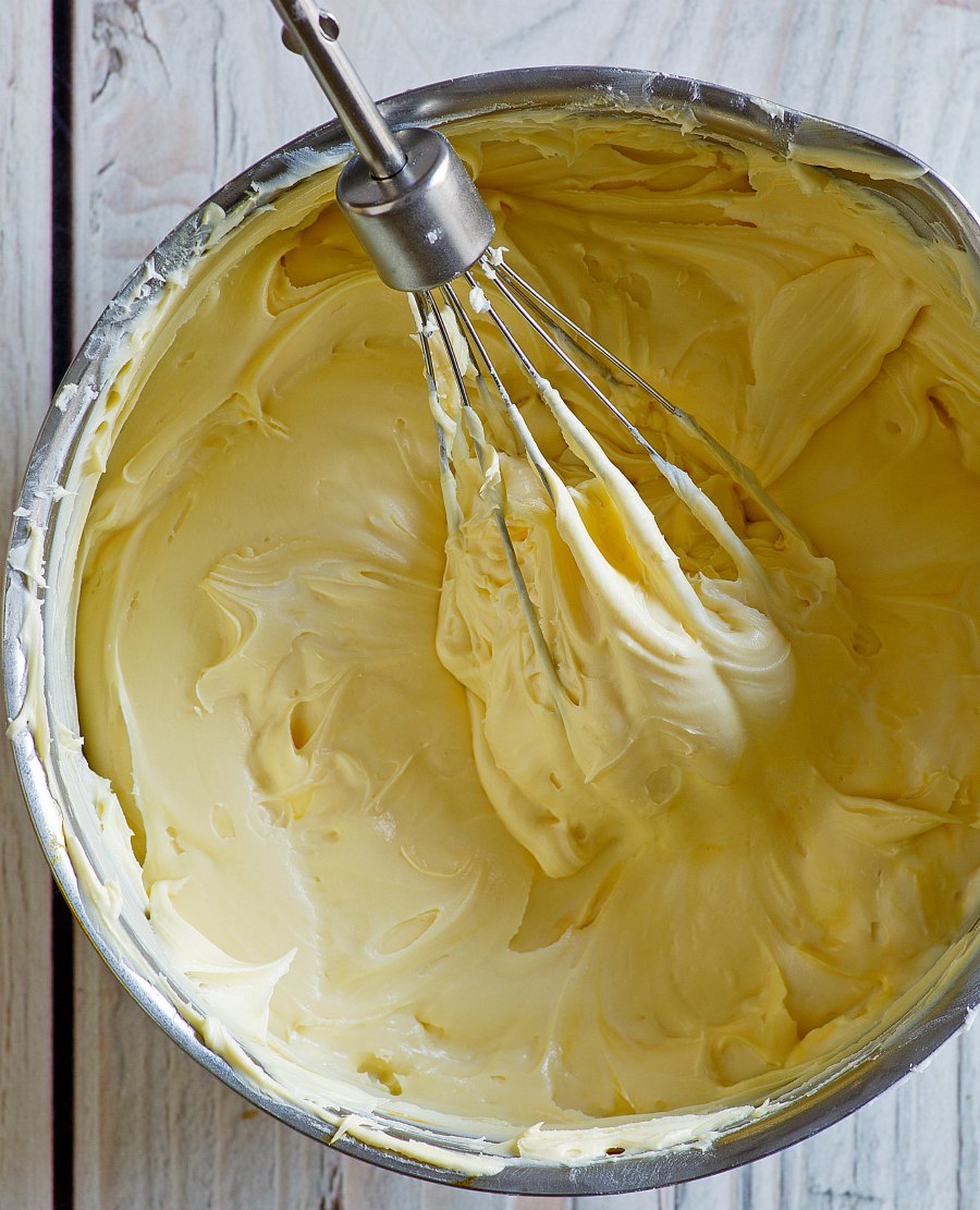 whisk in a bowl of pale yellow maple buttercream