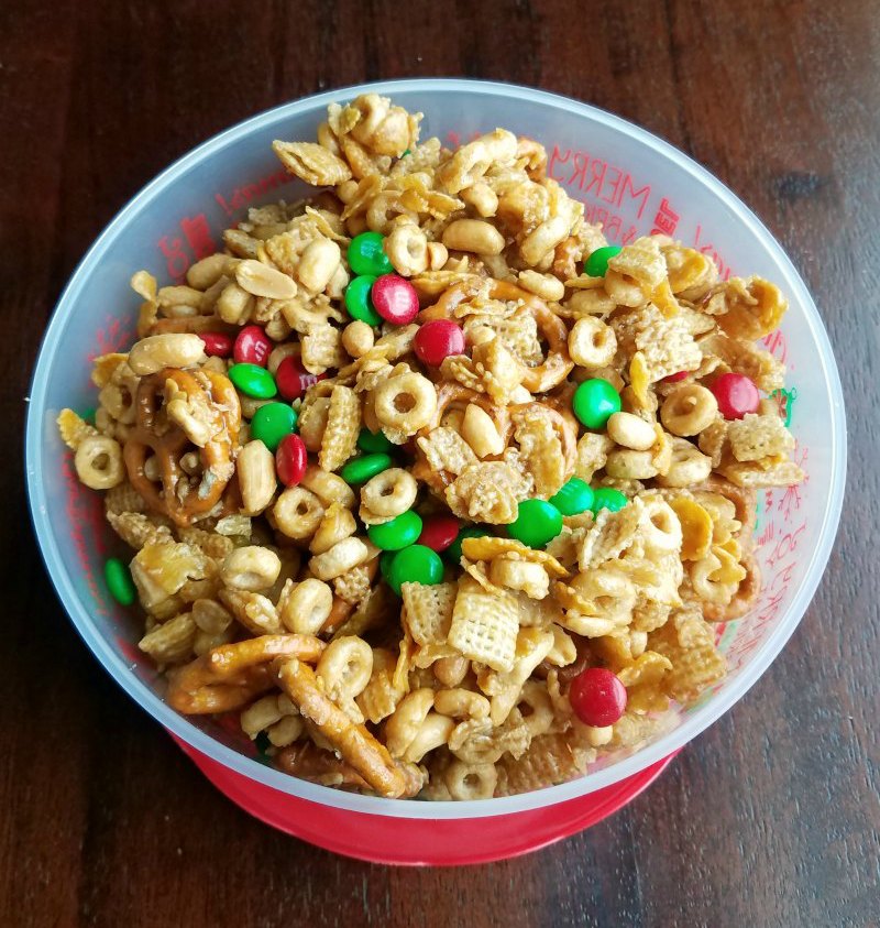 Tub full of sweet and salty caramel snack mix with cereal, bugles, candy and more.