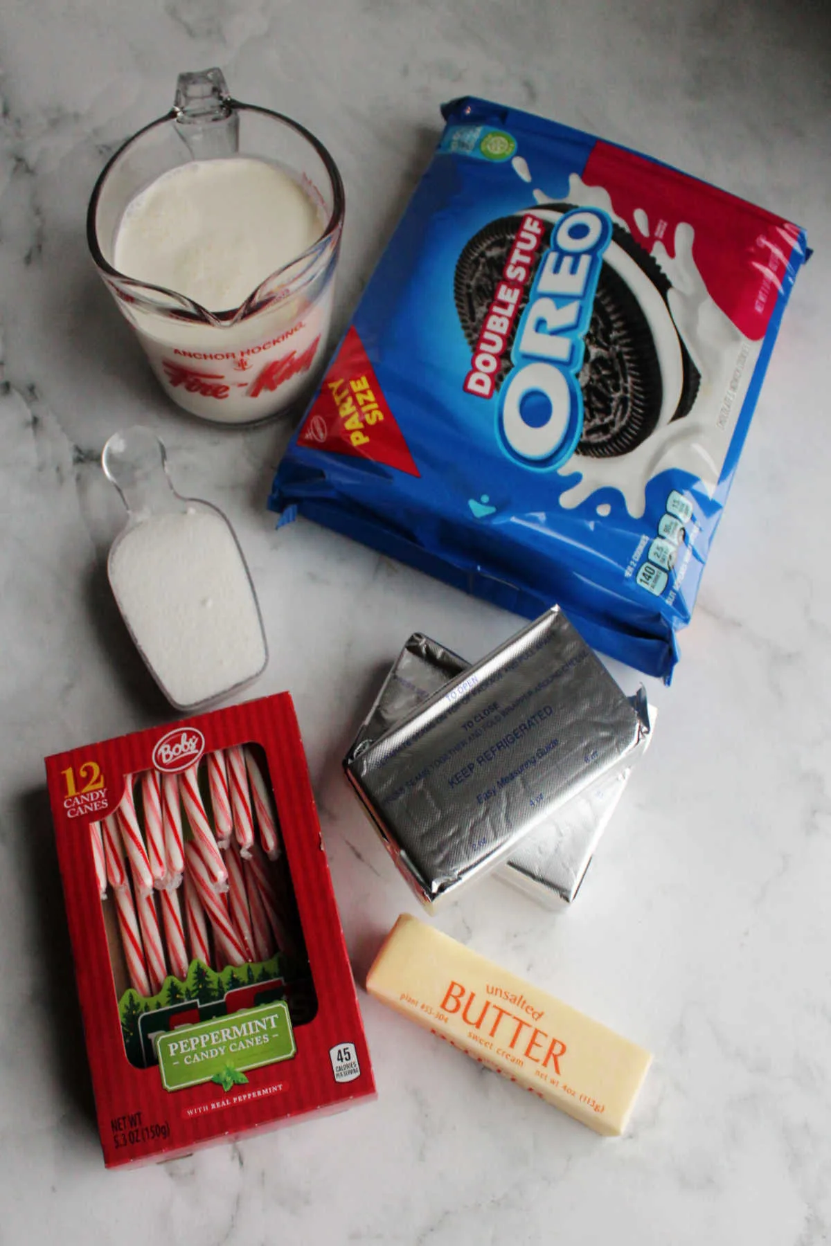 Ingredients including Oreos, cream cheese, cream, butter, sugar and candy canes ready to be made into no bake cheesecake.