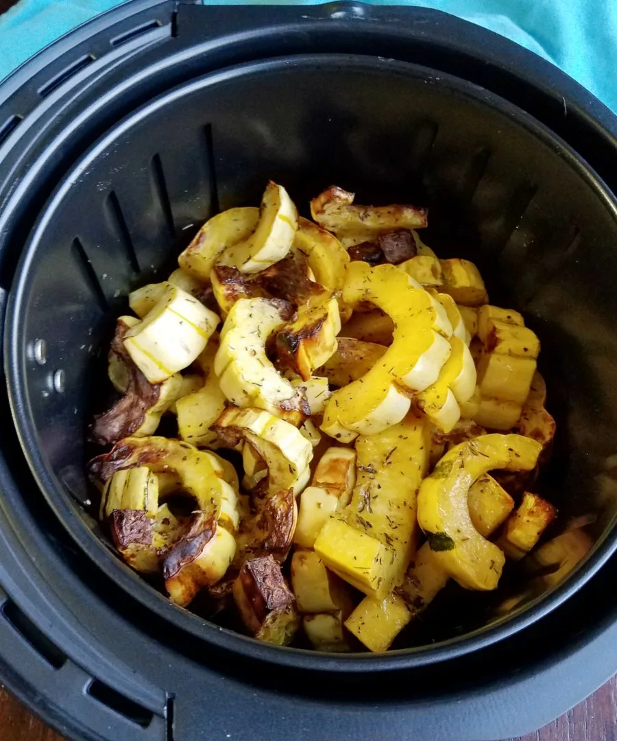 slices of delicata squash roasted in air fryer in basket ready to eat.