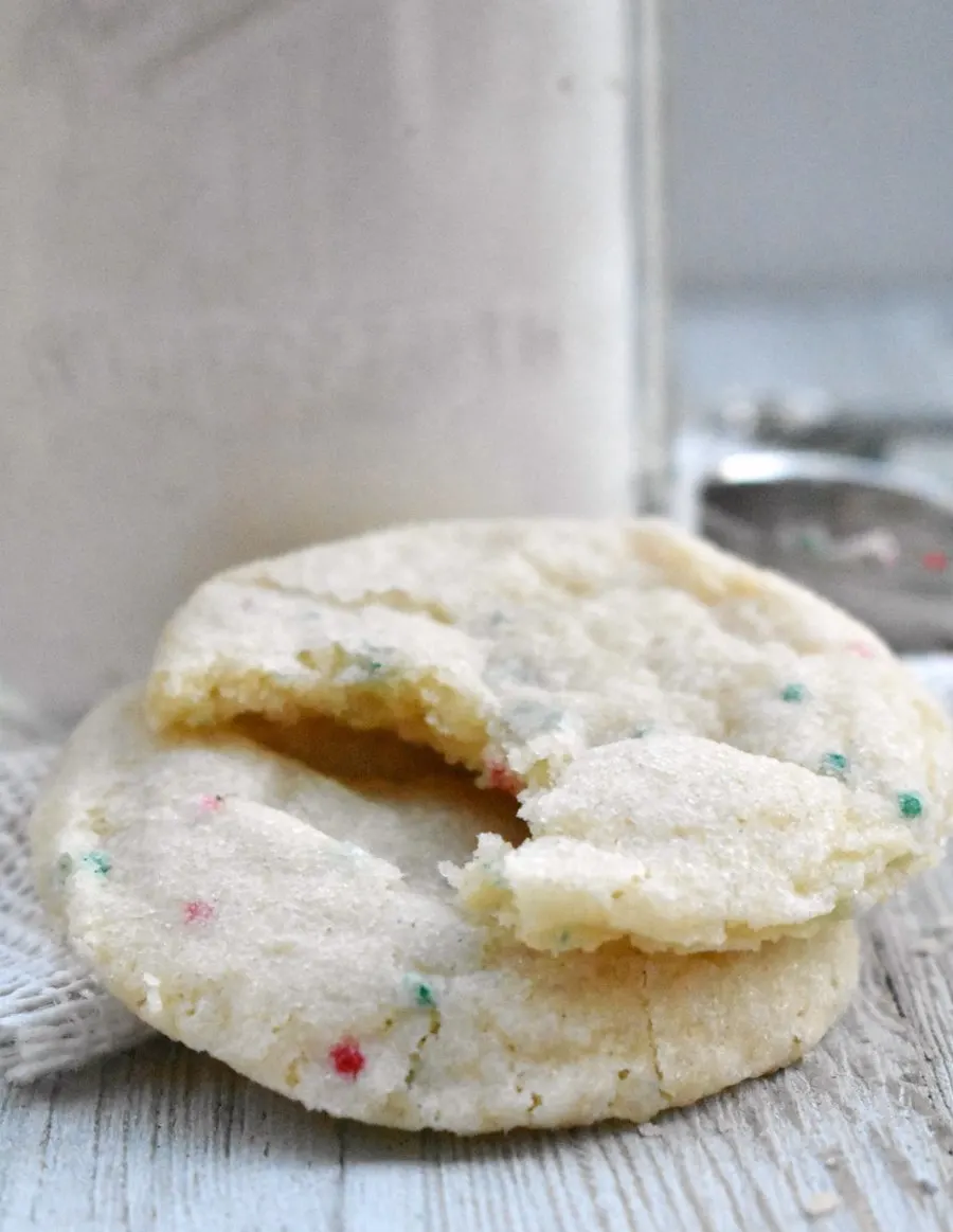 couple of sprinkle sugar cookies one with a bite taken out.