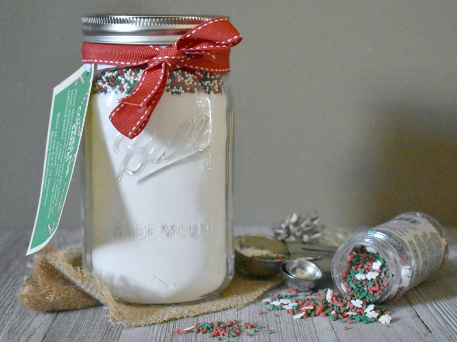 jar of dry ingredients for cookies and sprinkles with tipped sprinkle bottle nearby