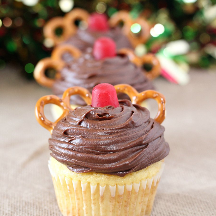 close up of a row of cupcakes decorated with chocolate frosting, a red gumdrop and pretzels to look like Rudolph 