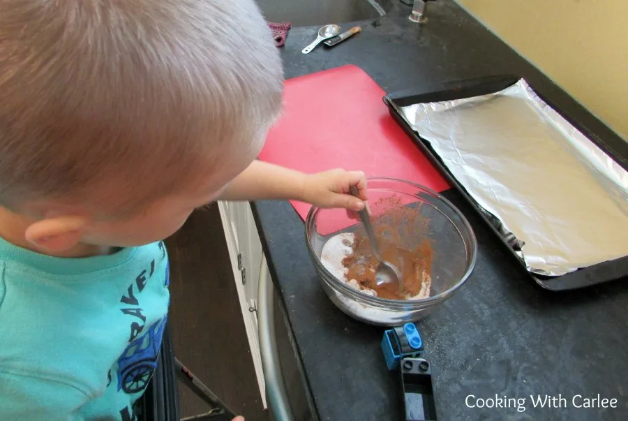 kid stirring together spice mixture for nuts.