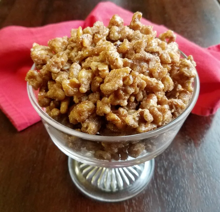 glass pedestal bowl filled with candied walnuts.