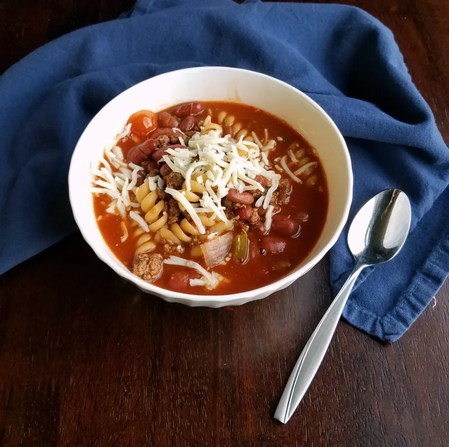 bowl of chili mac soup with cheese on top, ready to eat.