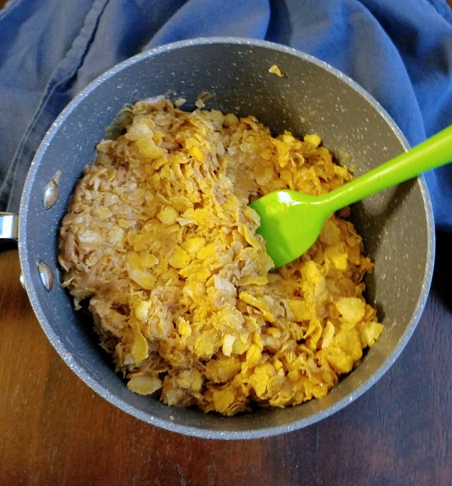 corn flakes stirred into peanut butter mixture in saucepan