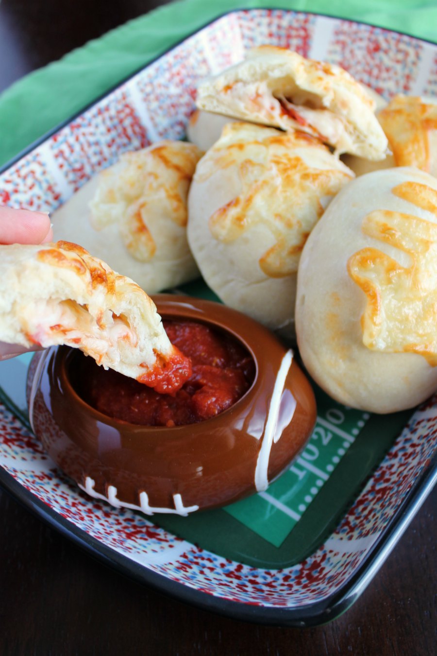dipping a stuffed pepperoni pizza football into dipping sauce,