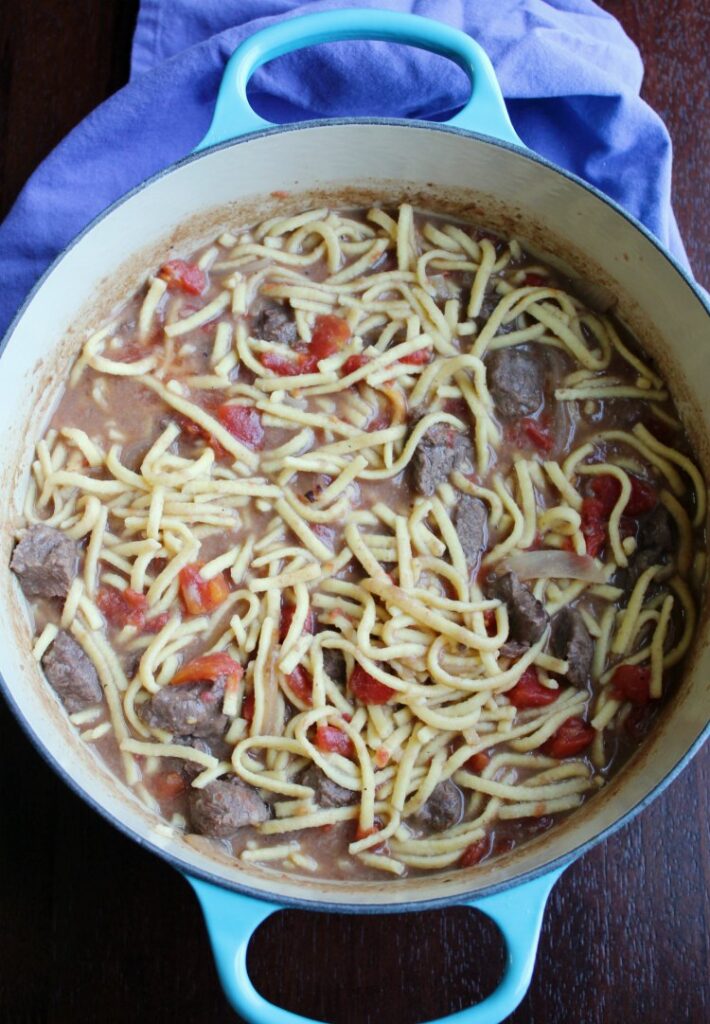 egg noodles in beef and tomato sauce in dutch oven.