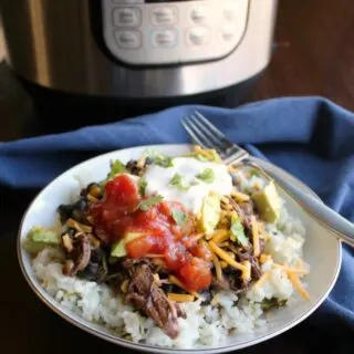 burrito bowl made of rice topped with salsa chicken, salsa, sour cream, cheese etc. in front of instant pot
