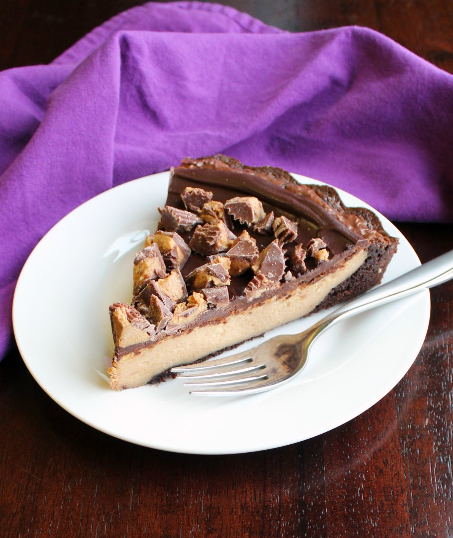 slice of peanut butter cheesecake brownie tart on plate with fork.