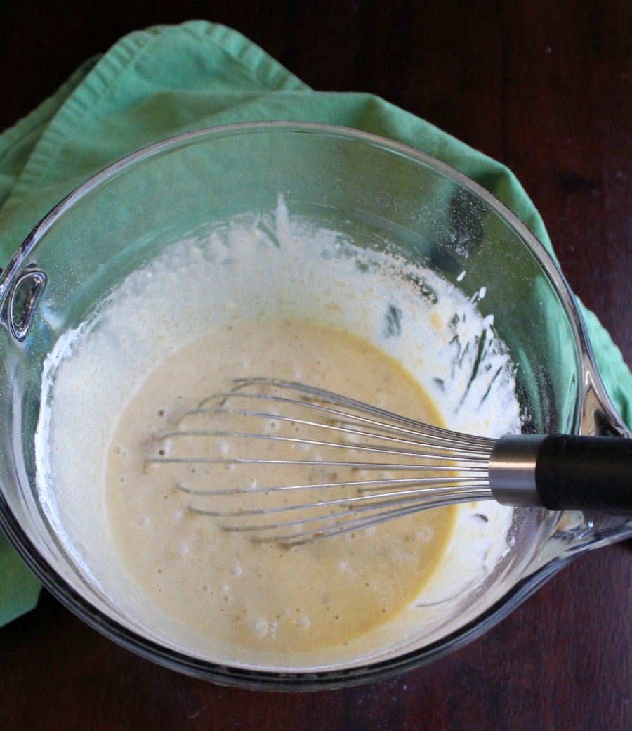 toll house pie batter in glass mixing bowl with whisk.