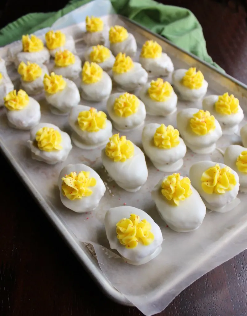 baking tray lined with wax paper and covered in rows of deviled egg cake balls.