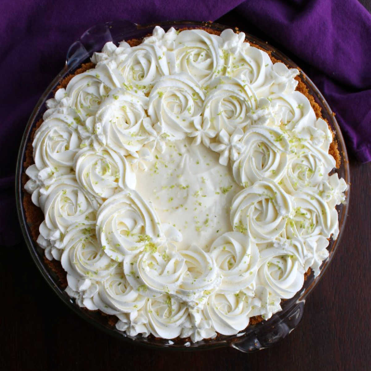 whole key lime pie with whipped cream rosettes and flowers on top.