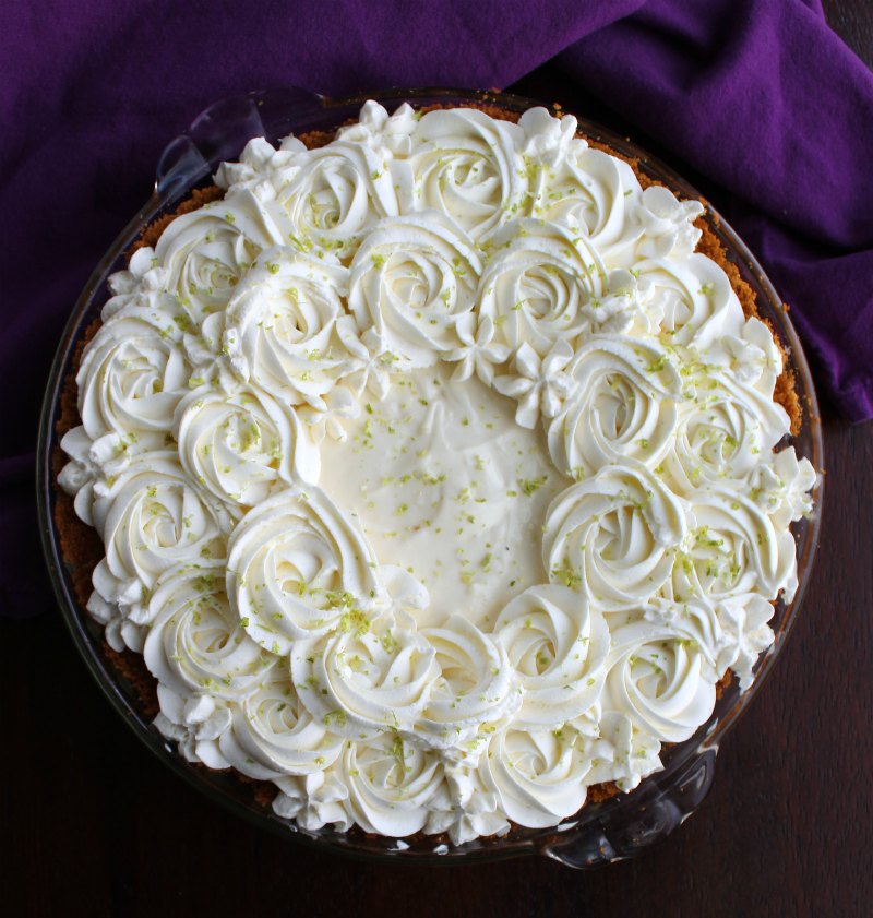 whole key lime pie with whipped cream rosettes and flowers on top