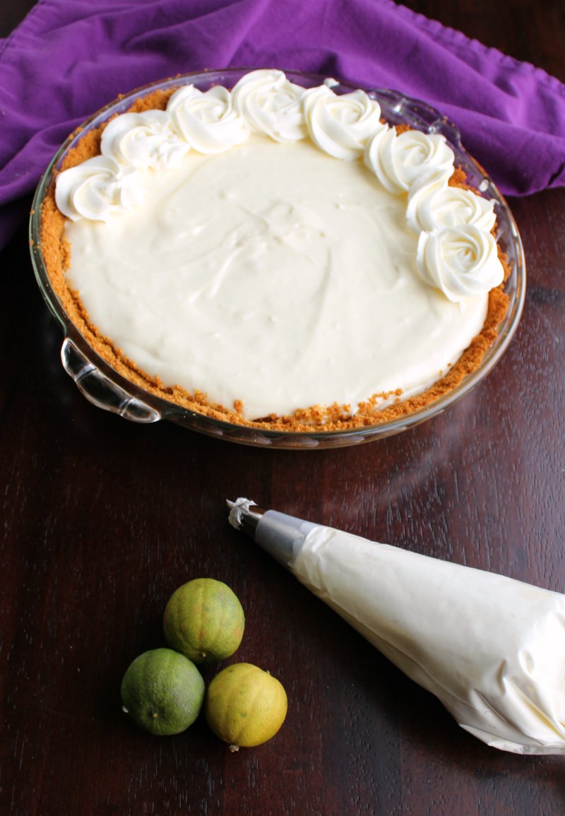 piping cream cheese whipped cream rosettes on top of key lime pie.