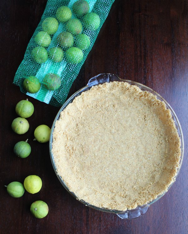 graham cracker crust in pie pan with a bag of small key limes.