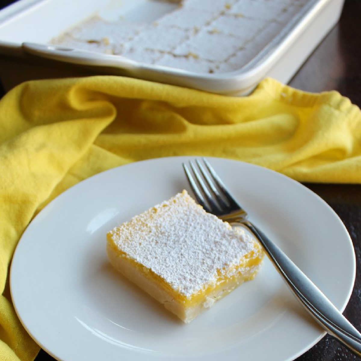 piece of powder sugar coated lemon bars on plate with fork