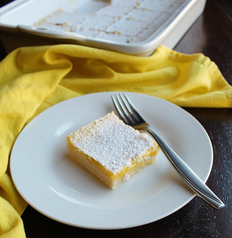 piece of powder sugar coated lemon bars on plate with fork