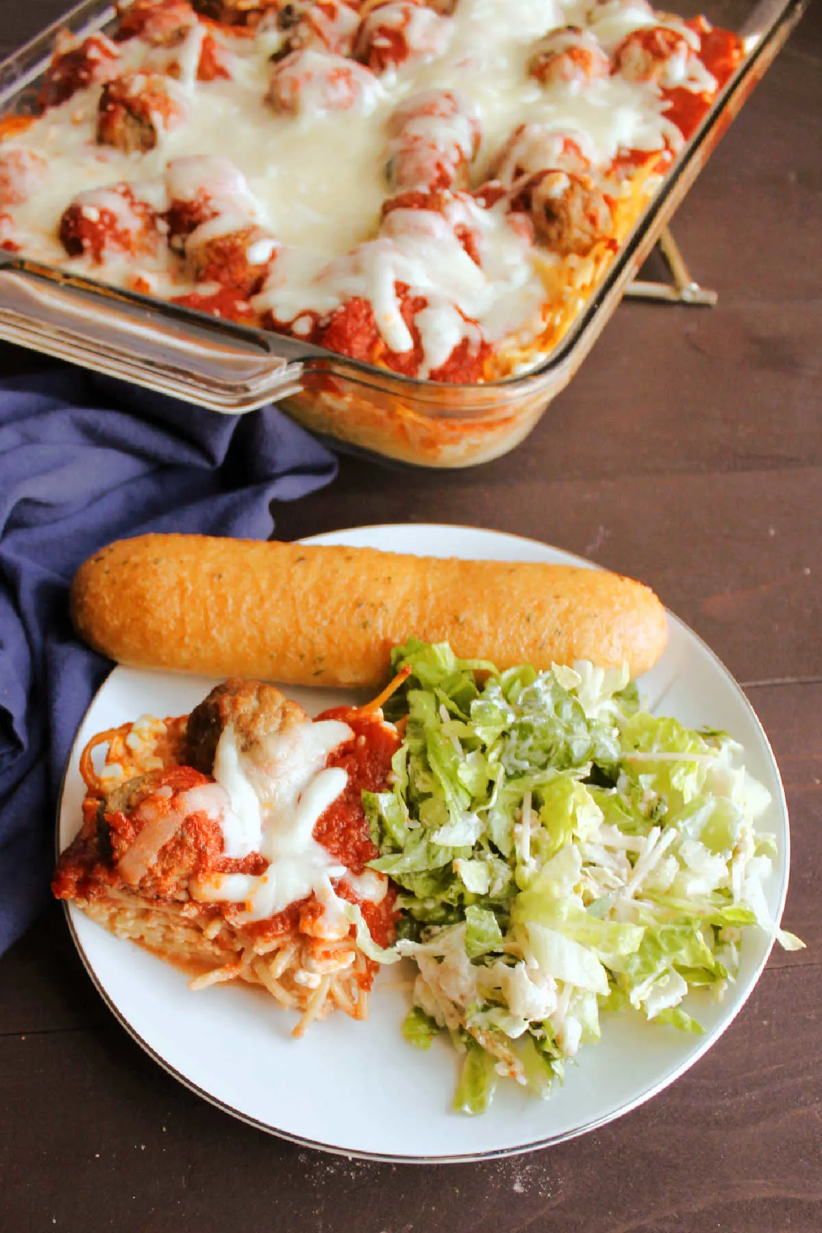 Dinner plate with spaghetti and meatball casserole, salad and breadstick ready to eat. 