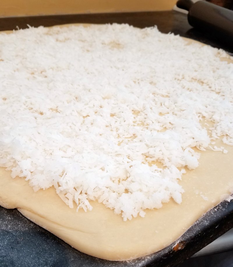 sweet roll dough brushed with a layer of melted coconut oil and sprinkled with sugar and coconut flakes.