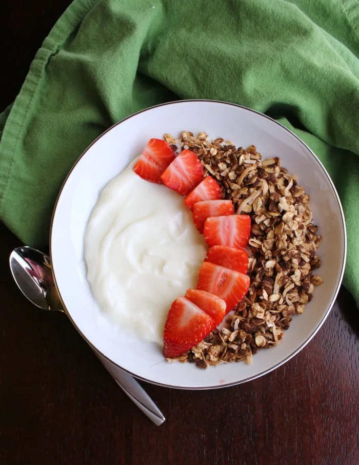 top view of bowl of yogurt with strawberries and chocolate granola.
