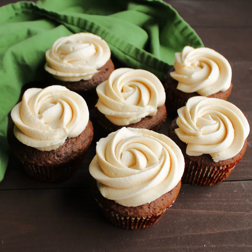 chocolate cupcakes topped with rosettes of light tan caramel buttercream ready to eat.
