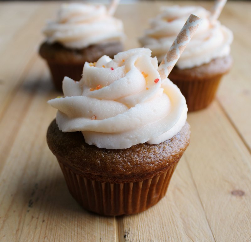 Sweet tea cupcakes topped with peach buttercream decorated with a paper straw and sprinkles.