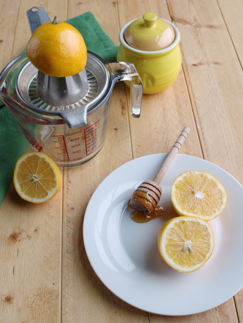 lemon half on juicer, lemons and honey pot all ready to be made into lemonade.