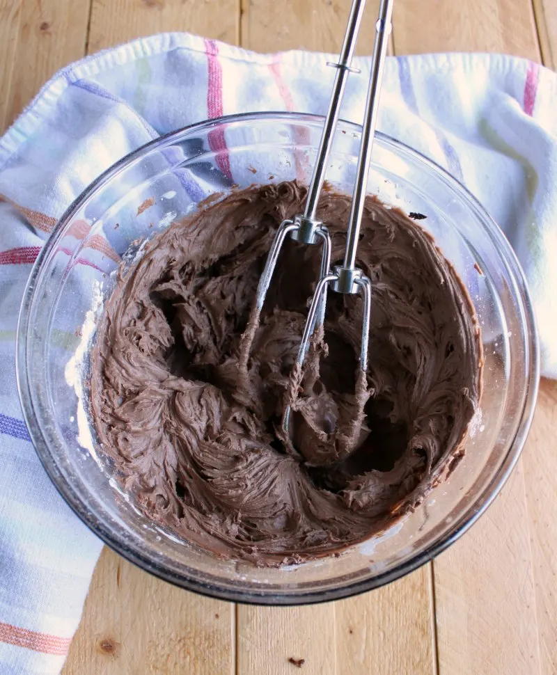 bowl of chocolate frosting with beaters.
