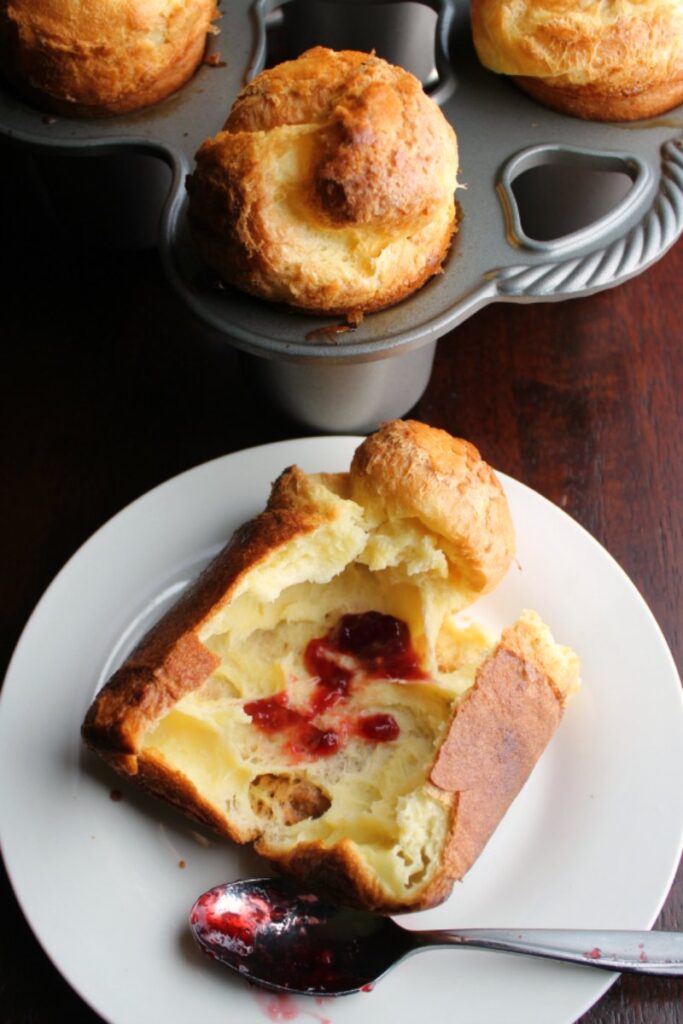 popover with preserves on a plate with big popovers in the pan in the background.