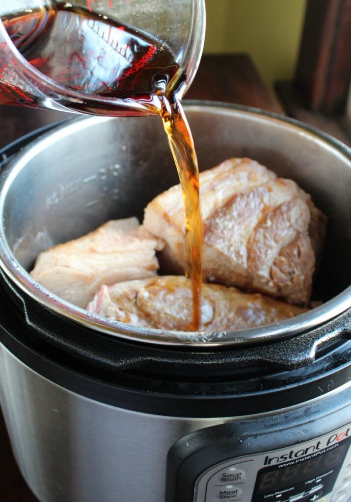 pouring root beer over pork in pressure cooker.