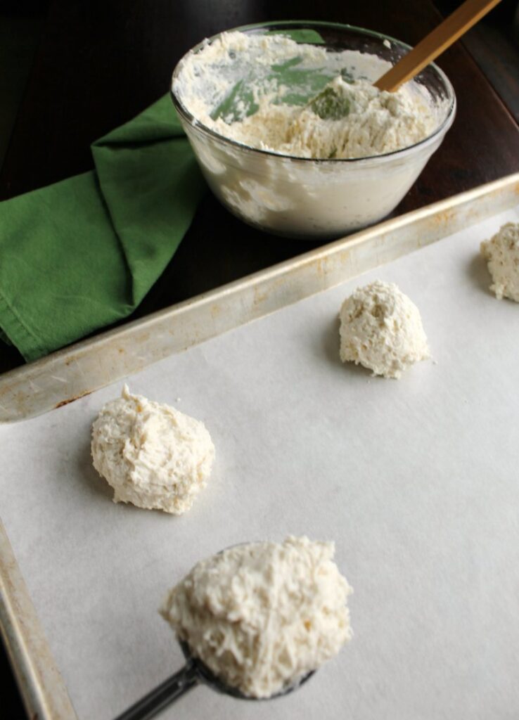 bowl of biscuit dough and mounds of yogurt biscuit dough on baking sheet.