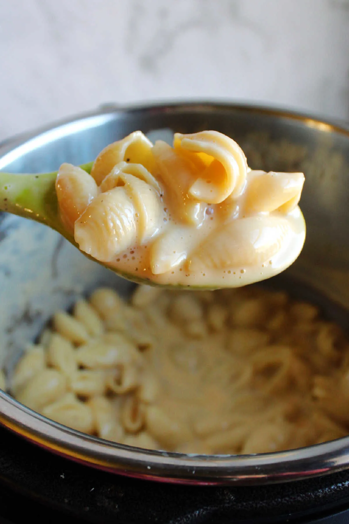 Serving spoon filled with cheesy instant pot Velveeta shells and cheese.