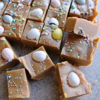 Smooth peanut butter fudge topped with pastel sprinkles and mini chocolate eggs, ready to eat.