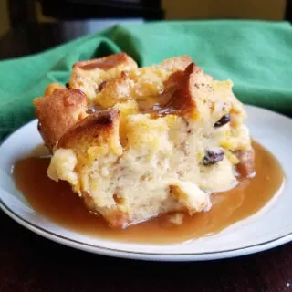 Piece of old fashioned bread pudding with raisins and maple sauce.