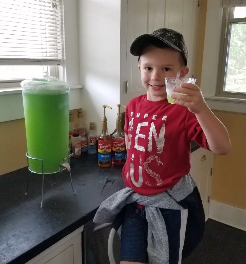 Little dude proudly showing off the first glass of green slime from the dispenser.