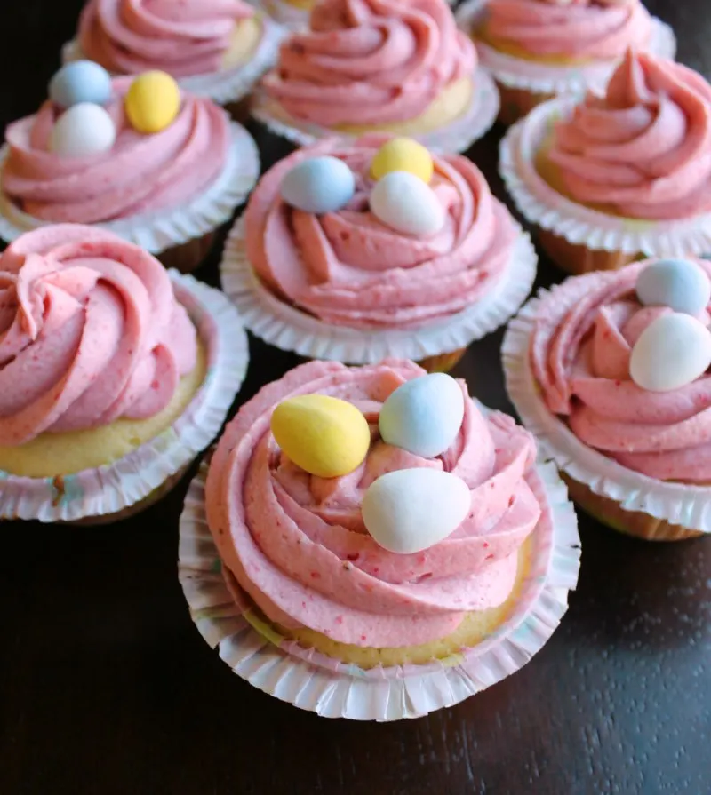 cupcakes with swirls of strawberry buttercream and mini chocolate eggs on top.
