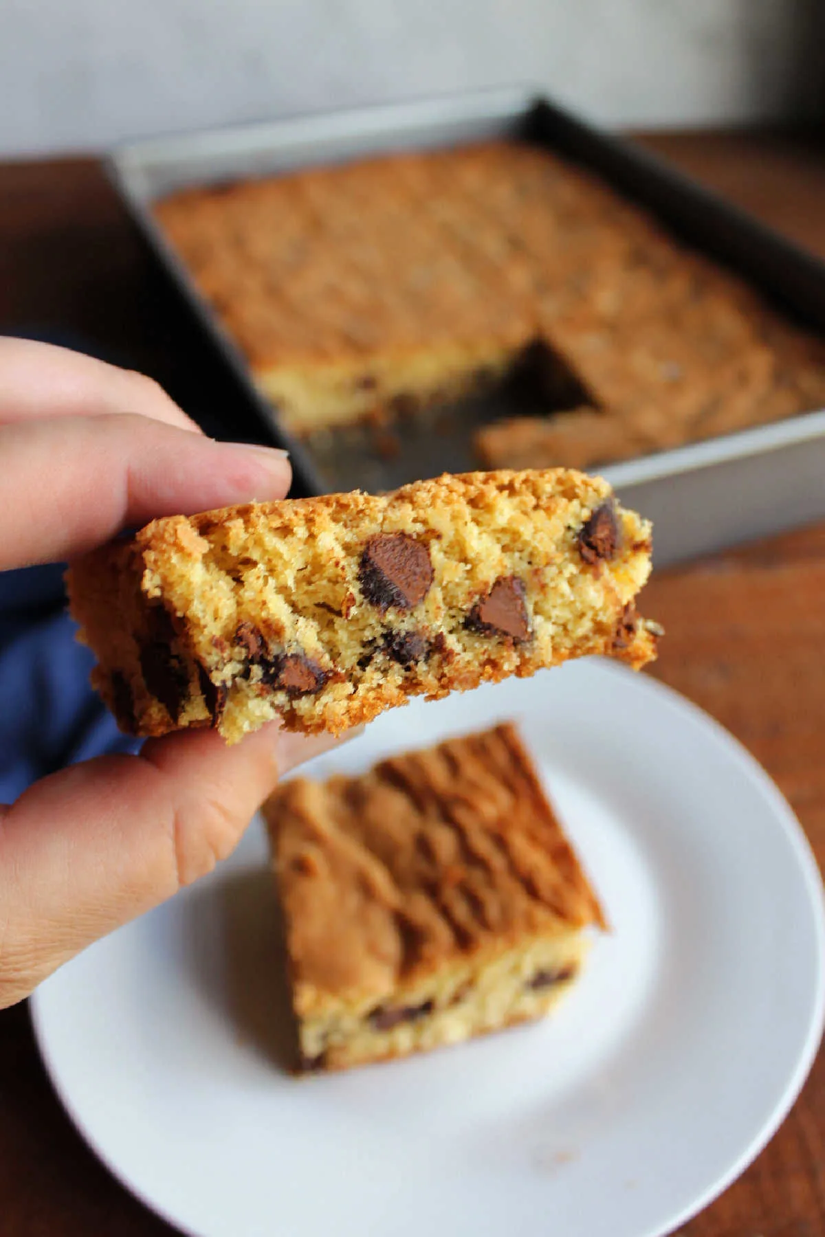 Hand holding chocolate chip brown sugar bar, ready to eat.