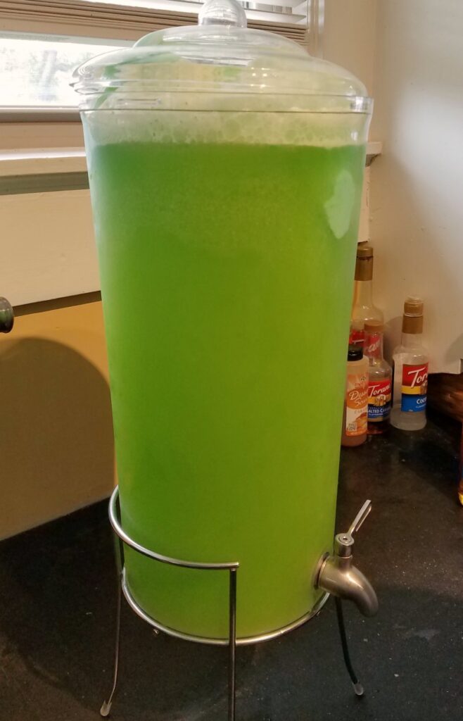Tall beverage dispenser full of green punch.