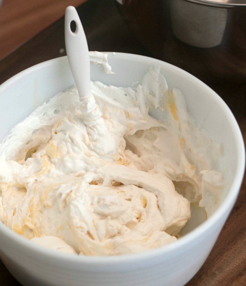 Putting whipped cream into a mixing bowl with pudding mixture.