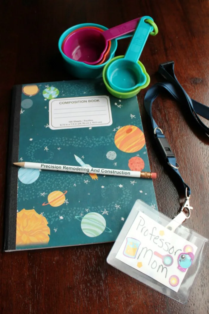 a composition notebook, pencil, name tag and measuring cup for the science kits. not pictured: safety glasses.