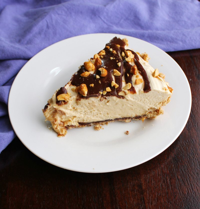 Slice of no bake peanut butter pie with fluff peanut butter filling, pretzel crust and layer of fudge.
