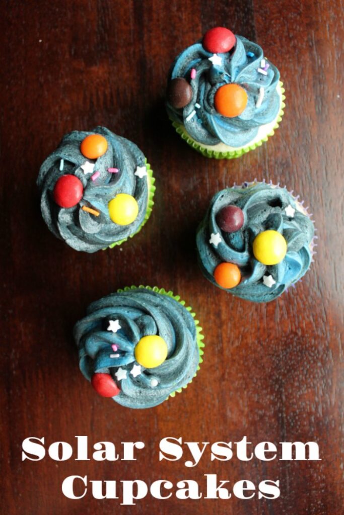 cupcakes with dark frosting and colored candy planets with star sprinkles.
