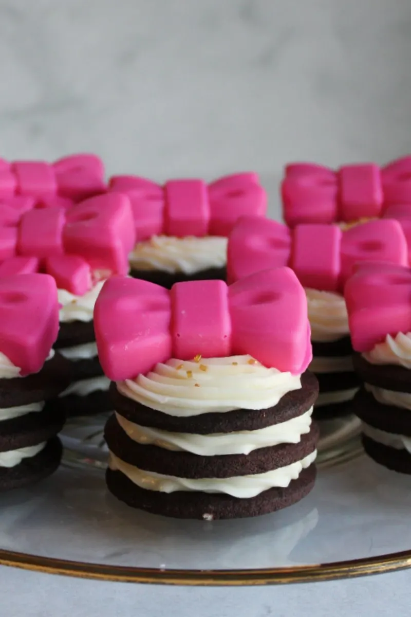 plate full of chocolate sandwich cookie stack with large pink chocolate bows on top.