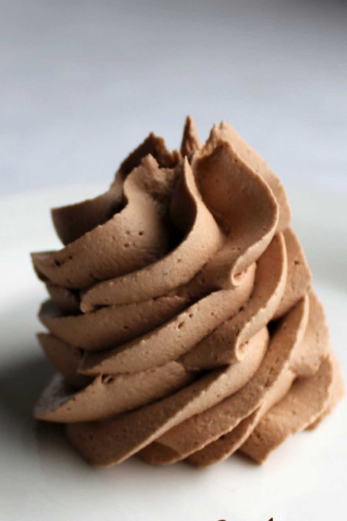 Piped swirl of lighter colored chocolate buttercream frosting.